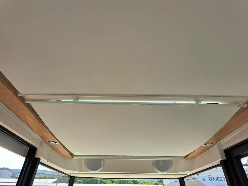 Modern interior ceiling with a wooden trim, integrated lighting, and speakers, creating a sleek, contemporary ambiance.
